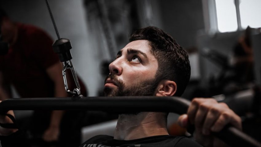 Muscular man working out with determination on gym equipment.